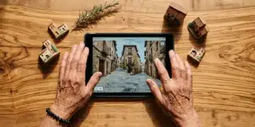 Manos de una anciana española con una tablet, mostrando un mapa digital de un pueblo medieval, sobre una mesa de madera de olivo con figuritas de arcilla y romero, simbolizando la fusión de tradición y tecnología en España.