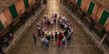 Ecos Contemporáneos: La Fusión de Cultura Española, Futuro Digital y Relatos Cotidianos Una vista aérea de un festival tradicional español, con personas vestidas con trajes regionales e interactuando con dispositivos móviles, bajo la luz dorada del atardecer.