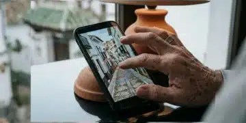 Mano envejecida sosteniendo un smartphone con un mapa digital de un pueblo español histórico, fusionando tradición y tecnología en España.